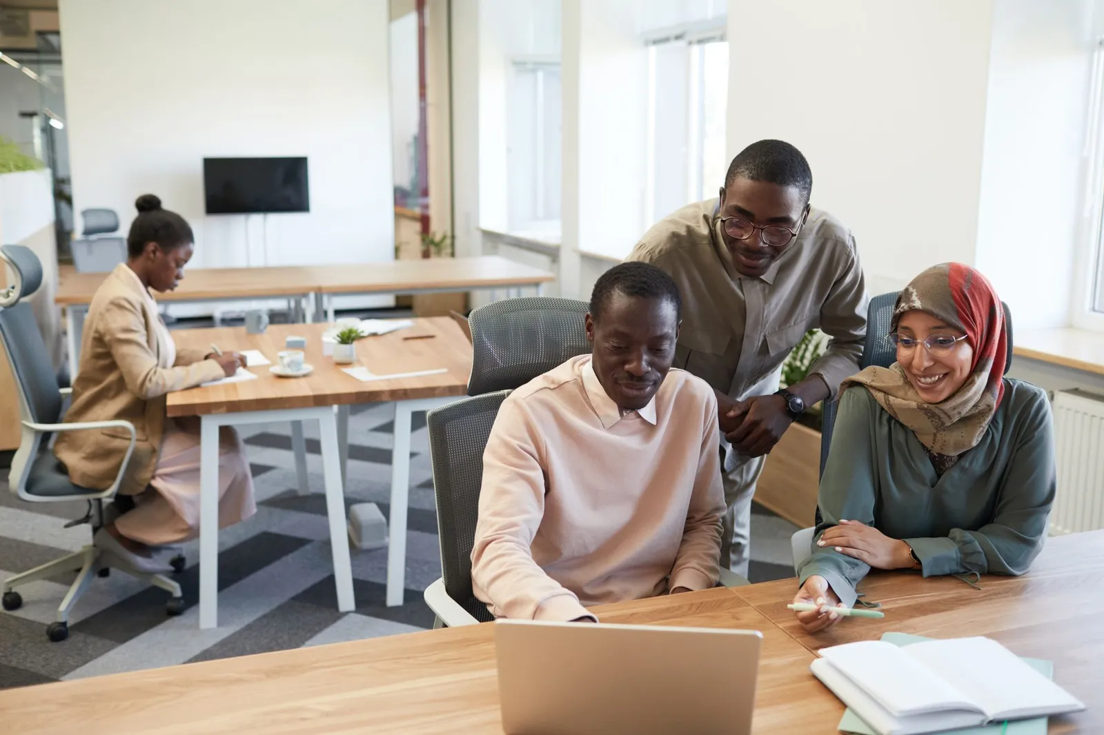 Three colleagues around a laptop in an office.